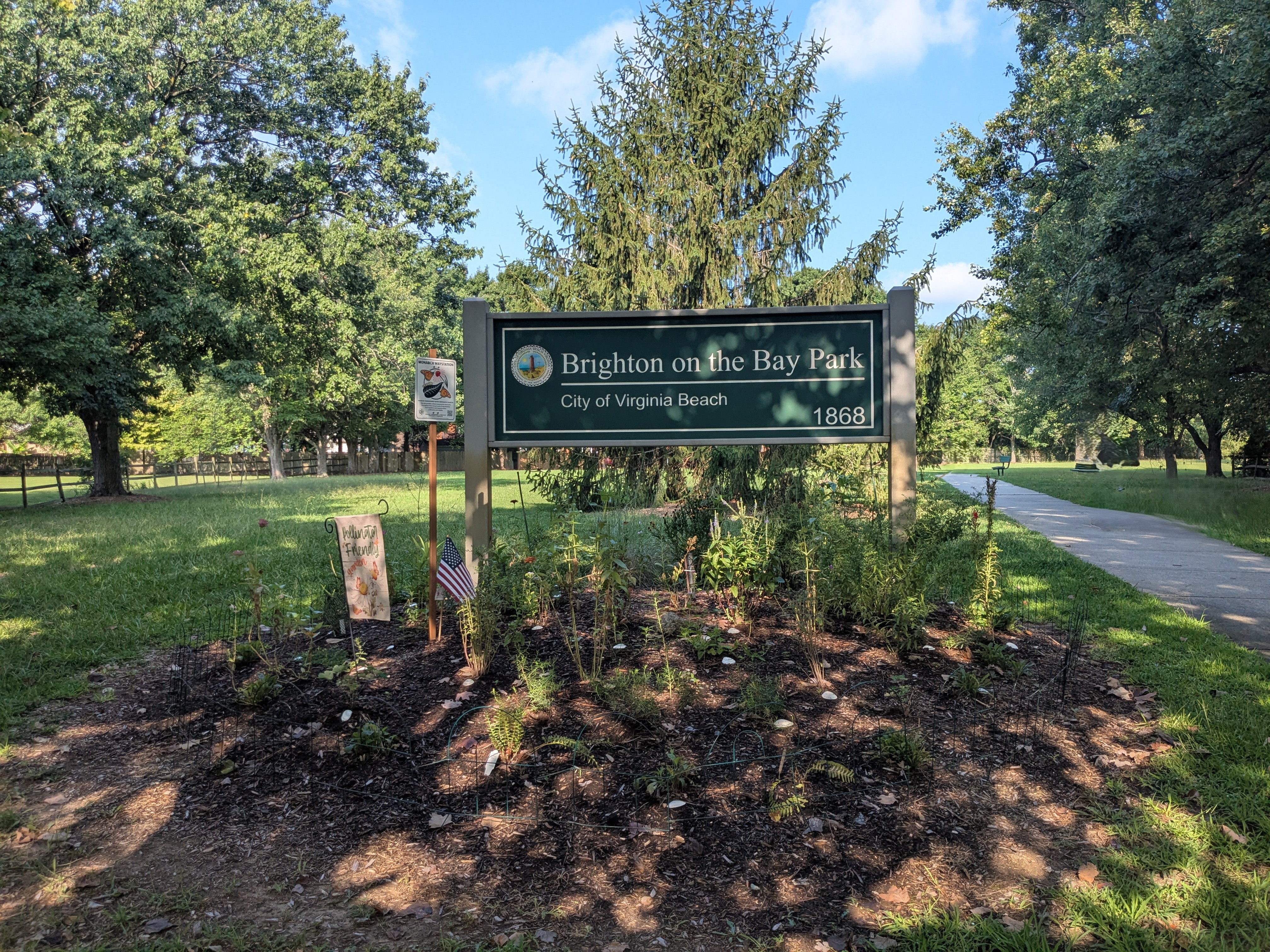 The Brighton on the Bay Park sign along a shaded walking path
